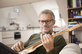 Oude man draagt ​​HOYA-progressieve lenzen terwijl hij gitaar speelt